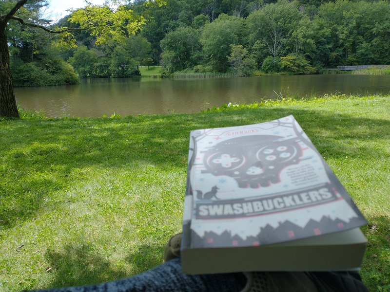 Swashbucklers book on my knee with lake in background